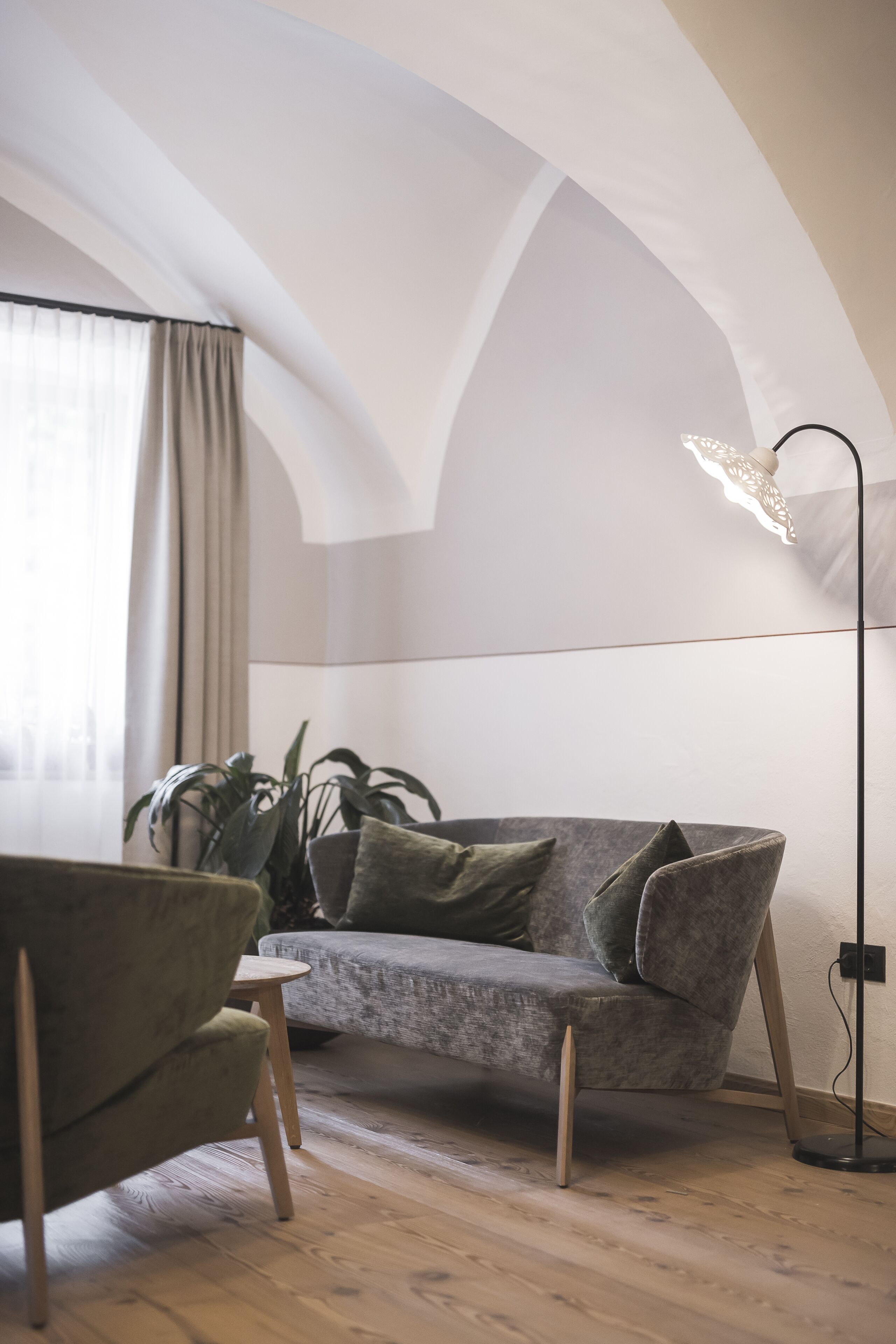 En moderne stue med en grå sofa, en grøn lænestol og en gulvlampe.