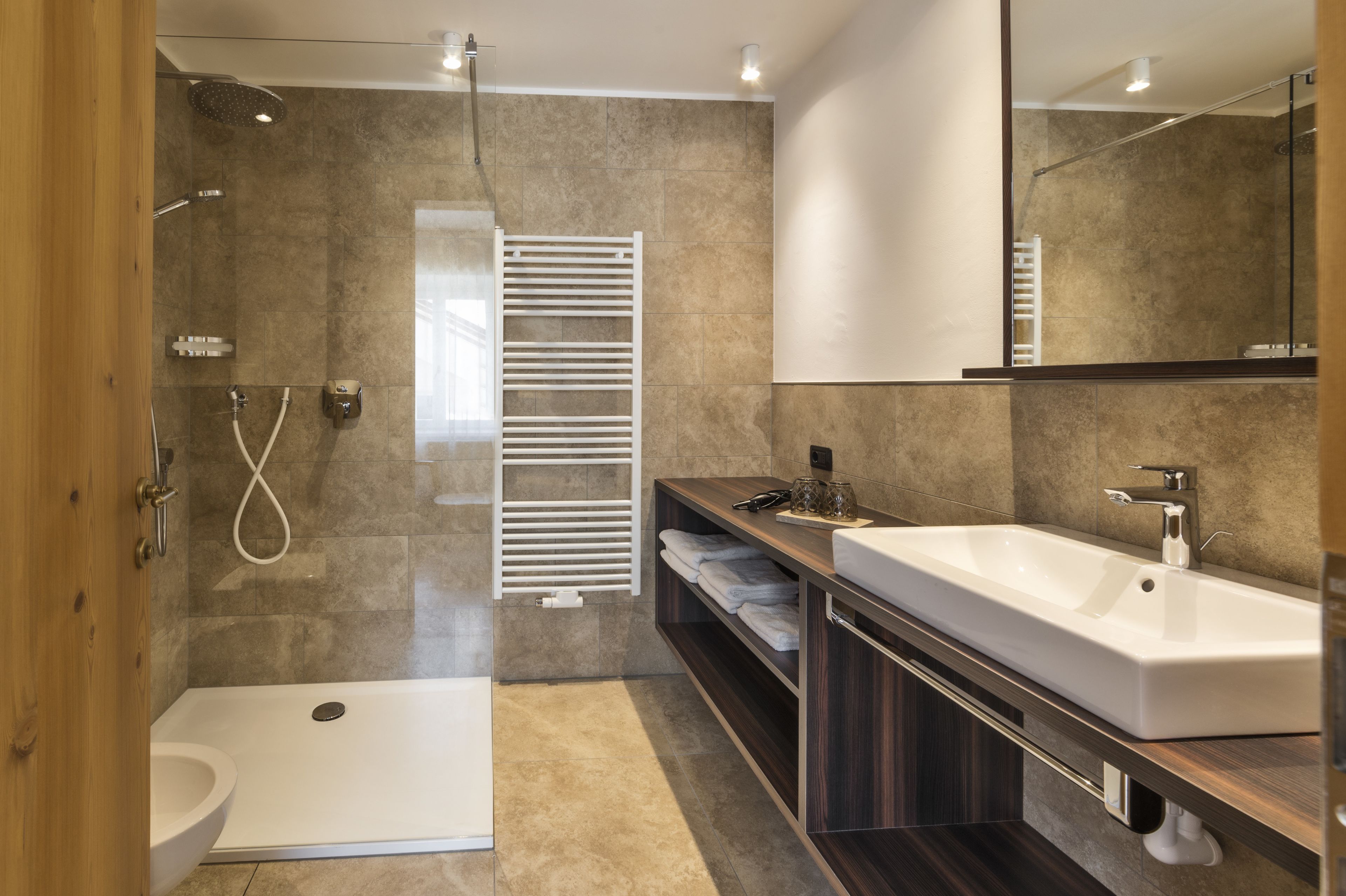 Une salle de bain moderne avec une douche à l’italienne, des toilettes, un lavabo et un porte-serviettes.