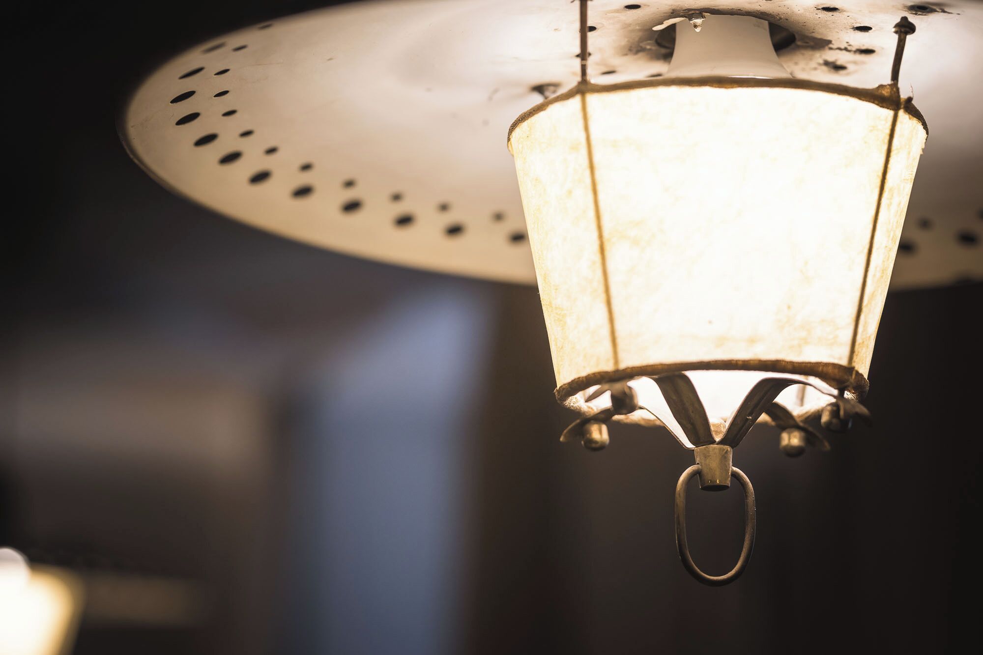 A hanging lantern with a metal frame and a glass enclosure, suspended from a ceiling fixture.