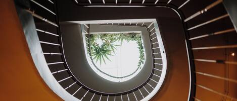 Un escalier en colimaçon offrant une vue sur le jardin central.