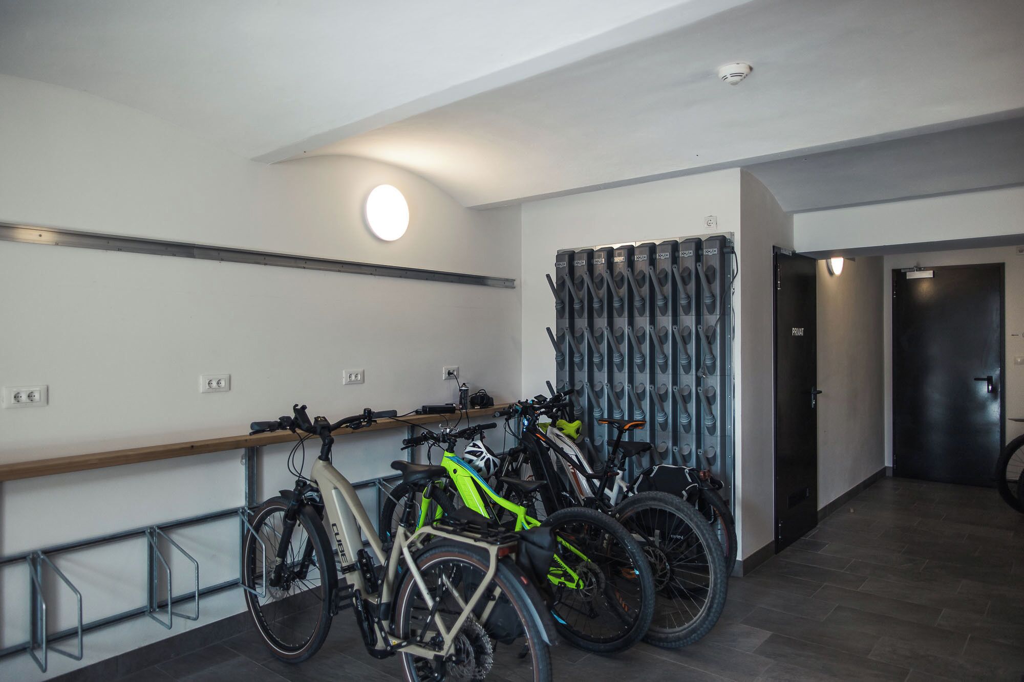 Un espacio interior moderno con bicicletas, un perchero para bicicletas en la pared y una puerta con la etiqueta 'PRIVATE'.