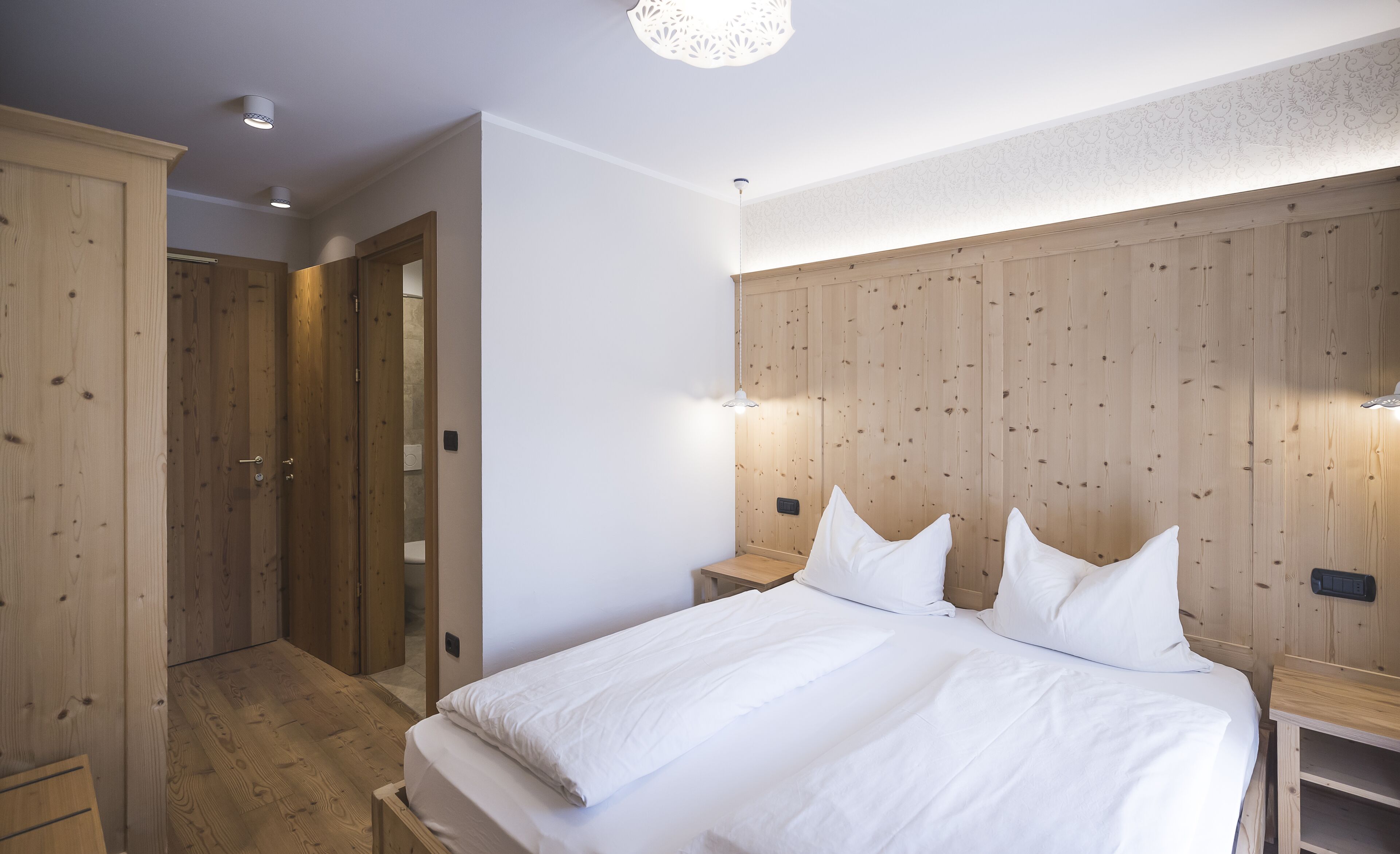 Ein Schlafzimmer mit einem hölzernen Kopfende, einem Bett mit weißer Bettwäsche und einem Holzschrank.