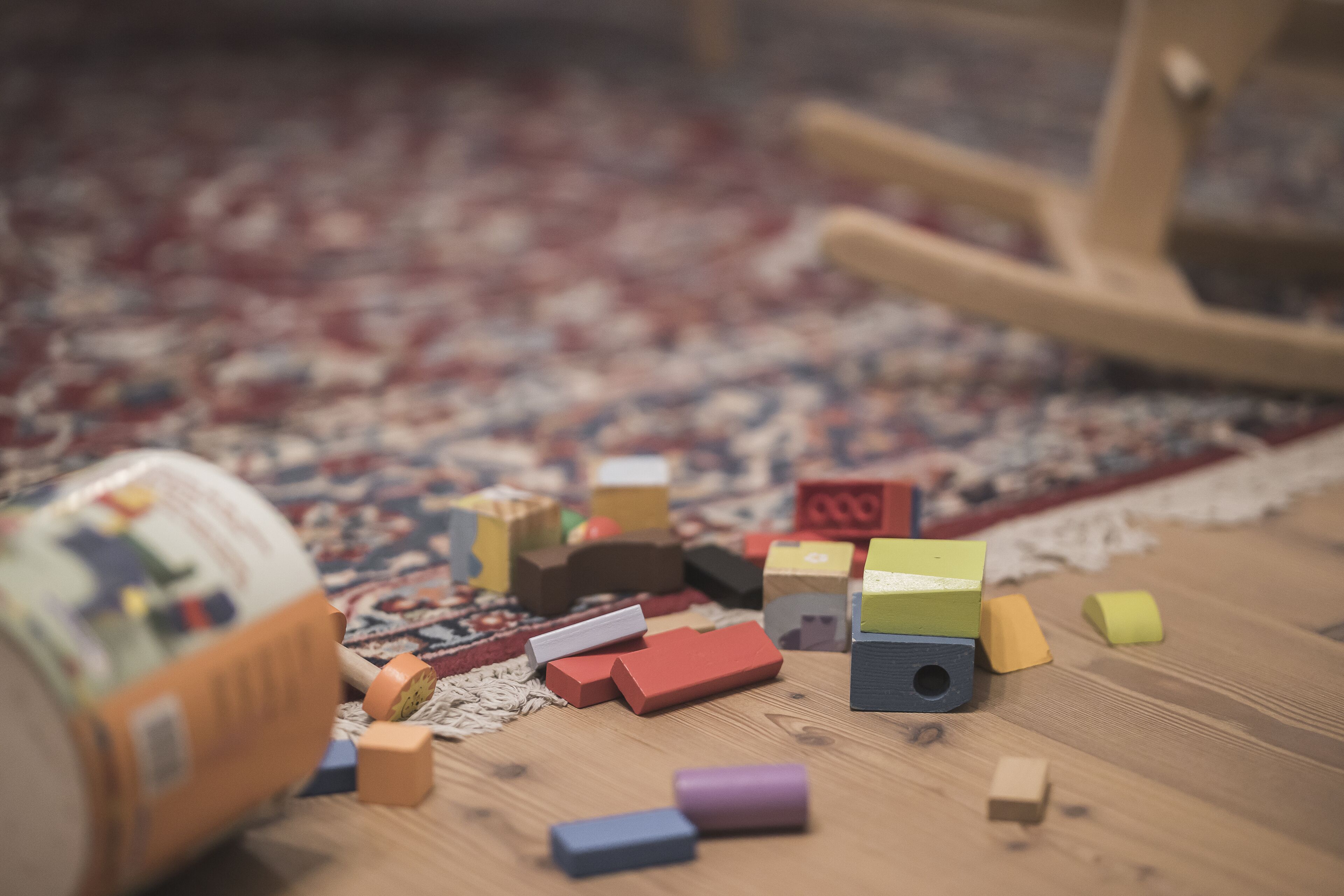 A wooden floor with scattered building blocks and a partially visible toy car.