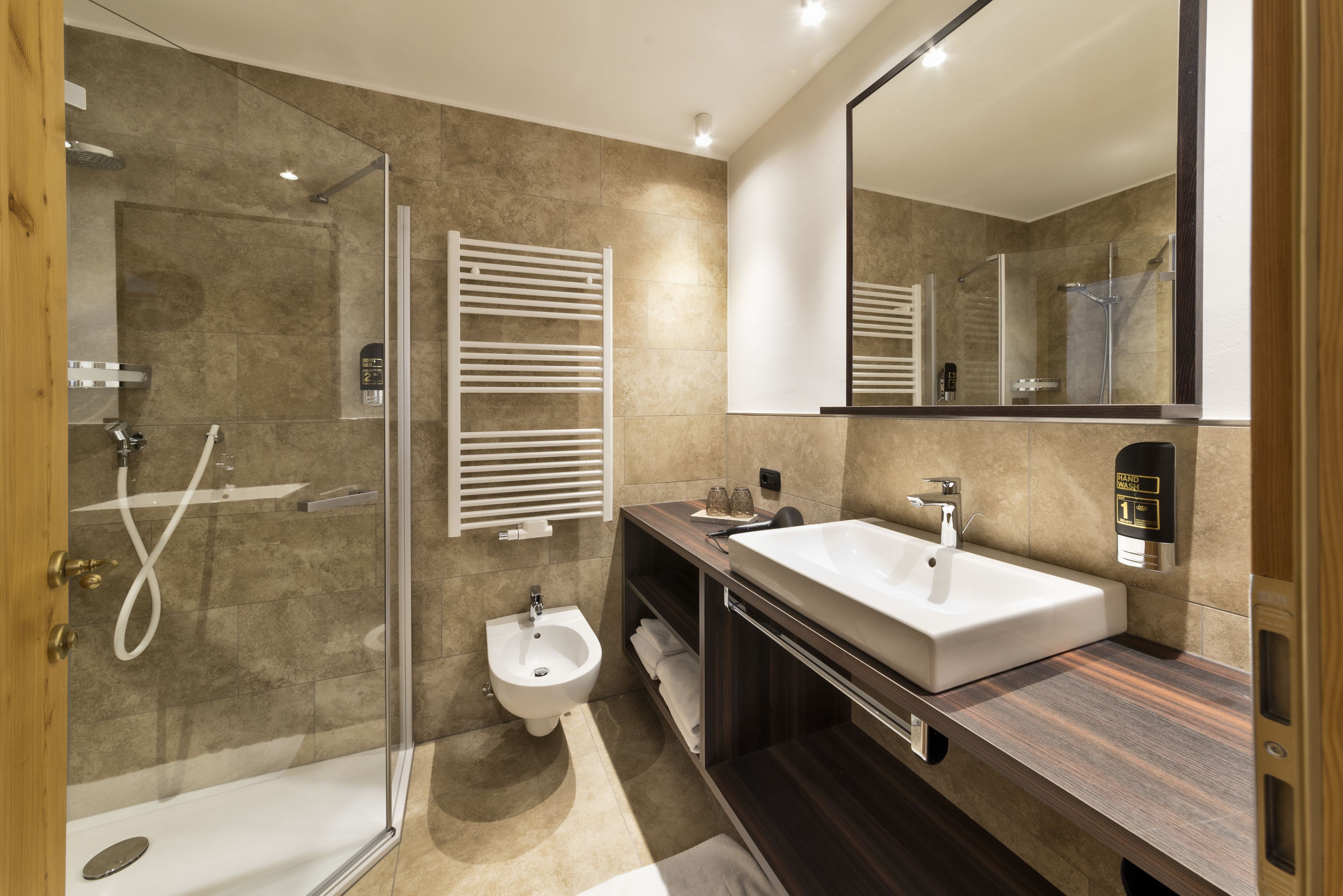 Un baño moderno con ducha de vidrio, lavamanos blanco y un bidé.