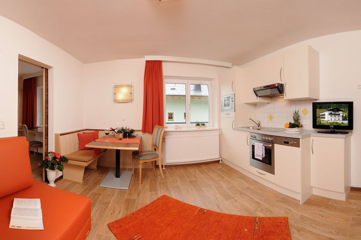 A compact living space with a sofa, dining table, and kitchenette.