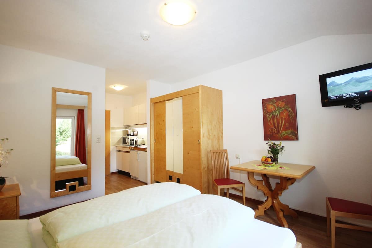 A hotel room with a bed, a desk, a chair, a television, and a painting on the wall.