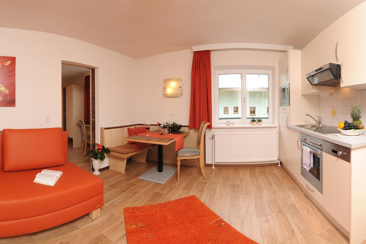 A compact living space with a sofa, dining table, and kitchenette.