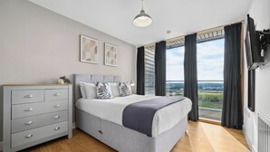 Une chambre à coucher avec un lit, une commode et une grande fenêtre donnant sur un beau paysage.