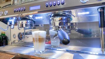 A coffee machine with multiple buttons and a digital display, a glass of coffee, and a glass of water on the counter.