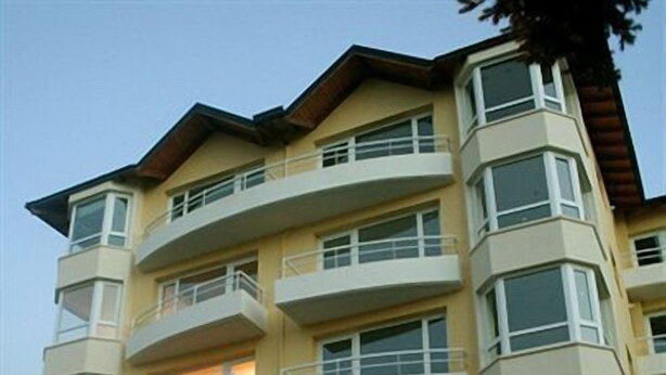 A multi-story residential building with balconies, large windows, and a stone facade.