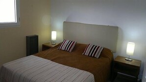 A hotel room with a single bed, two bedside tables, a lamp on each table, and a window on the left wall.