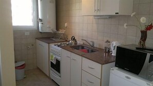 A compact kitchen with white cabinets, a built-in oven, a microwave, and a sink.