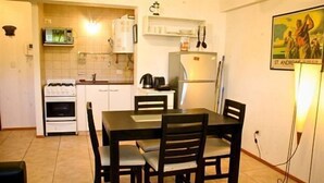 A compact kitchen with a dining area, featuring a stove, microwave, refrigerator, and a table with chairs.