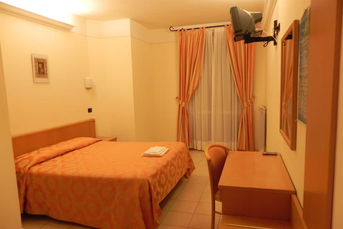 A hotel room with a bed, a desk, and a chair.