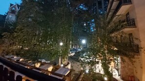 A nighttime view of a narrow street with buildings on either side, trees lining the street, and a few parked cars. - Meranda (Spezzano della Sila)