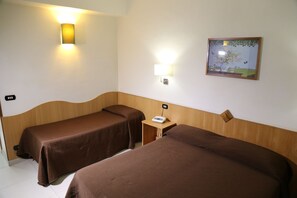 A hotel room with two single beds, a bedside table with a phone, a wall-mounted light, and a framed picture. - Meranda (Spezzano della Sila)