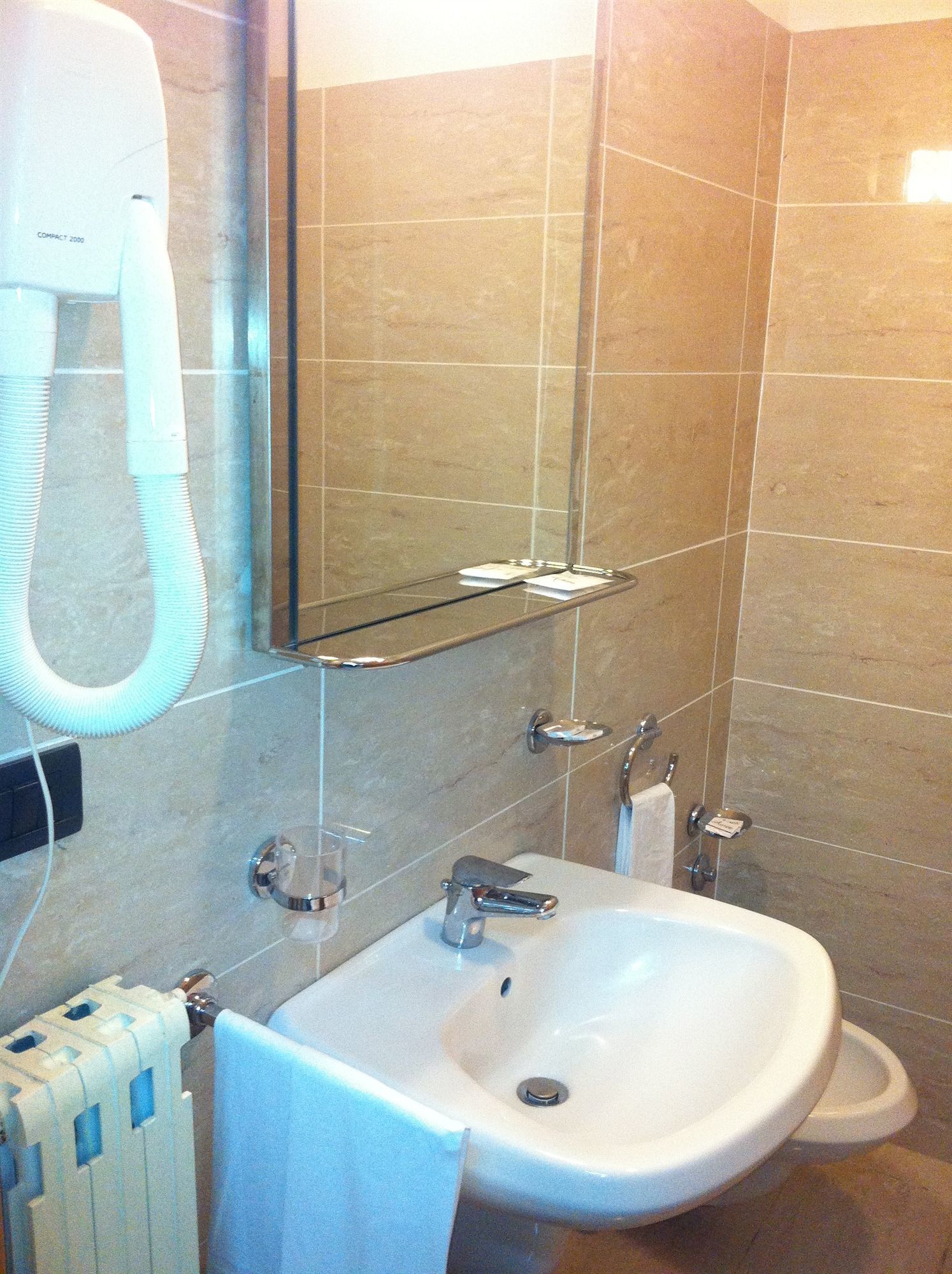 Een badkamer met een witte wastafel, een spiegel, een handdoekhouder en een haardroger.