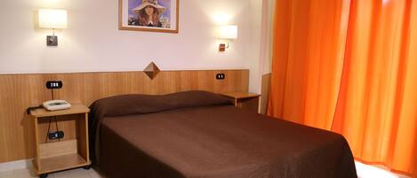 Una habitación de hotel con una cama, dos mesitas de noche, un teléfono y un cuadro en la pared.