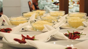 A buffet table with clear glass bowls of food, white napkins, and red chili peppers on plates. - Meranda (Spezzano della Sila)