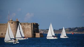 A coastal scene with sailboats near a historic stone building.