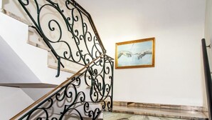 A staircase with ornate black metal railings and a marble floor. - The Originals Boutique, Hôtel La Baie de Morlaix (Carantec)