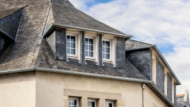 Ein Hotel mit einer Stein-Fassade, großen Fenstern und einem Schild mit der Aufschrift "HOTEL DE LA BAIE DE MORLAIX".