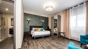 Ein modernes Schlafzimmer mit einem großen Bett, Holzboden, einem gemusterten Wand und einem durch eine offene Tür einsehbaren Badezimmer.