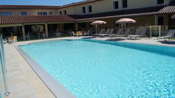 Relax by the pool surrounded by lounge chairs and umbrellas.