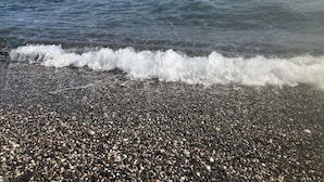 Uma praia de pedrinhas com ondas quebrando na costa.