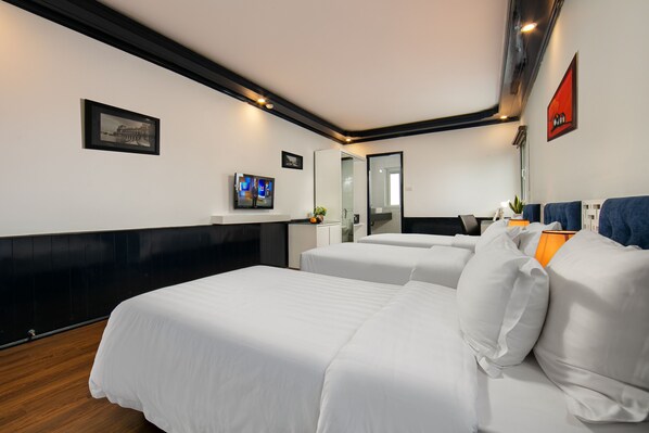 A hotel room with two beds, a TV, a desk, and a mirror.