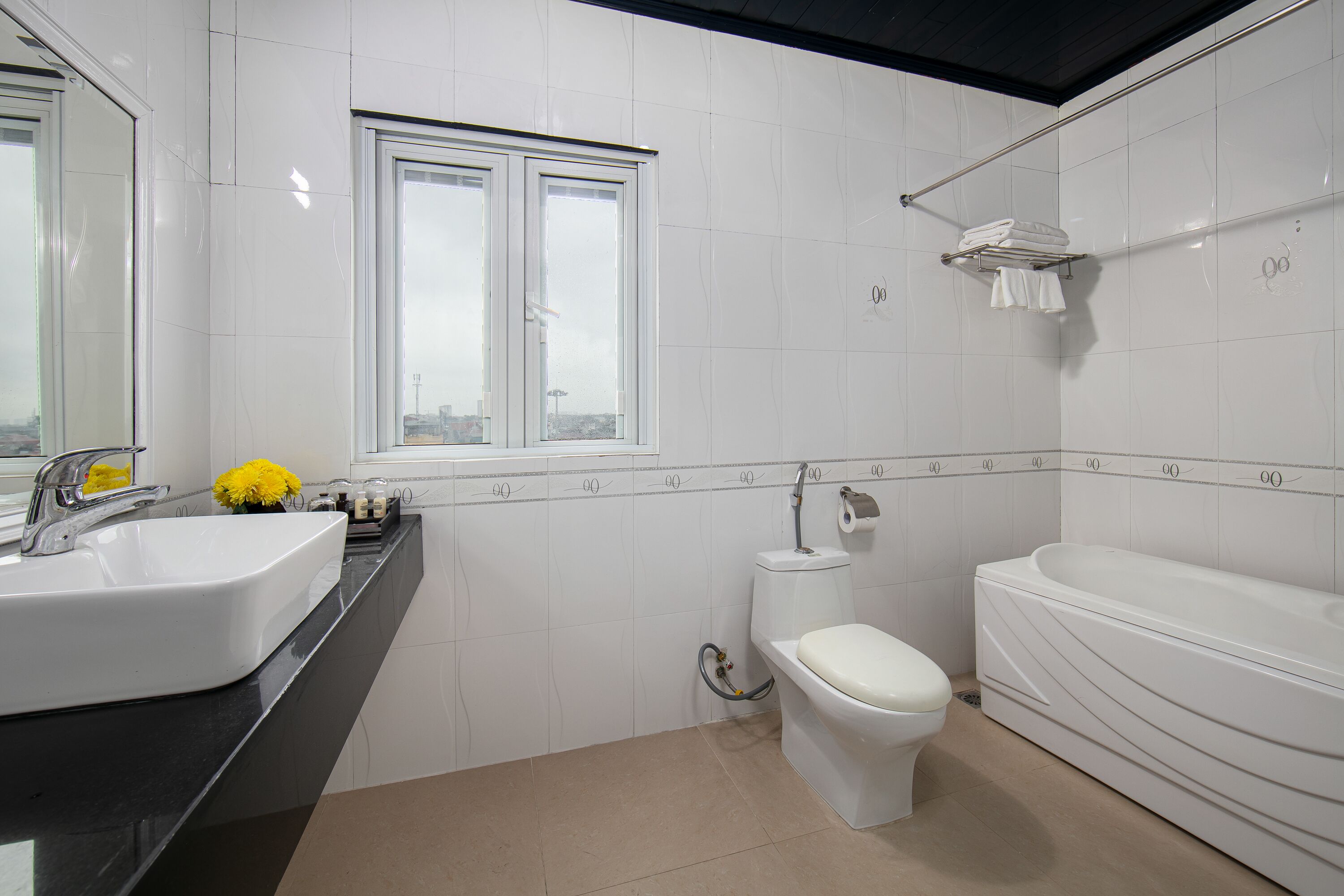 Une salle de bain moderne avec une grande fenêtre, un lavabo blanc, des toilettes et une baignoire.