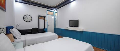 A hotel room with two beds, a desk, a chair, a TV, and a mirror.