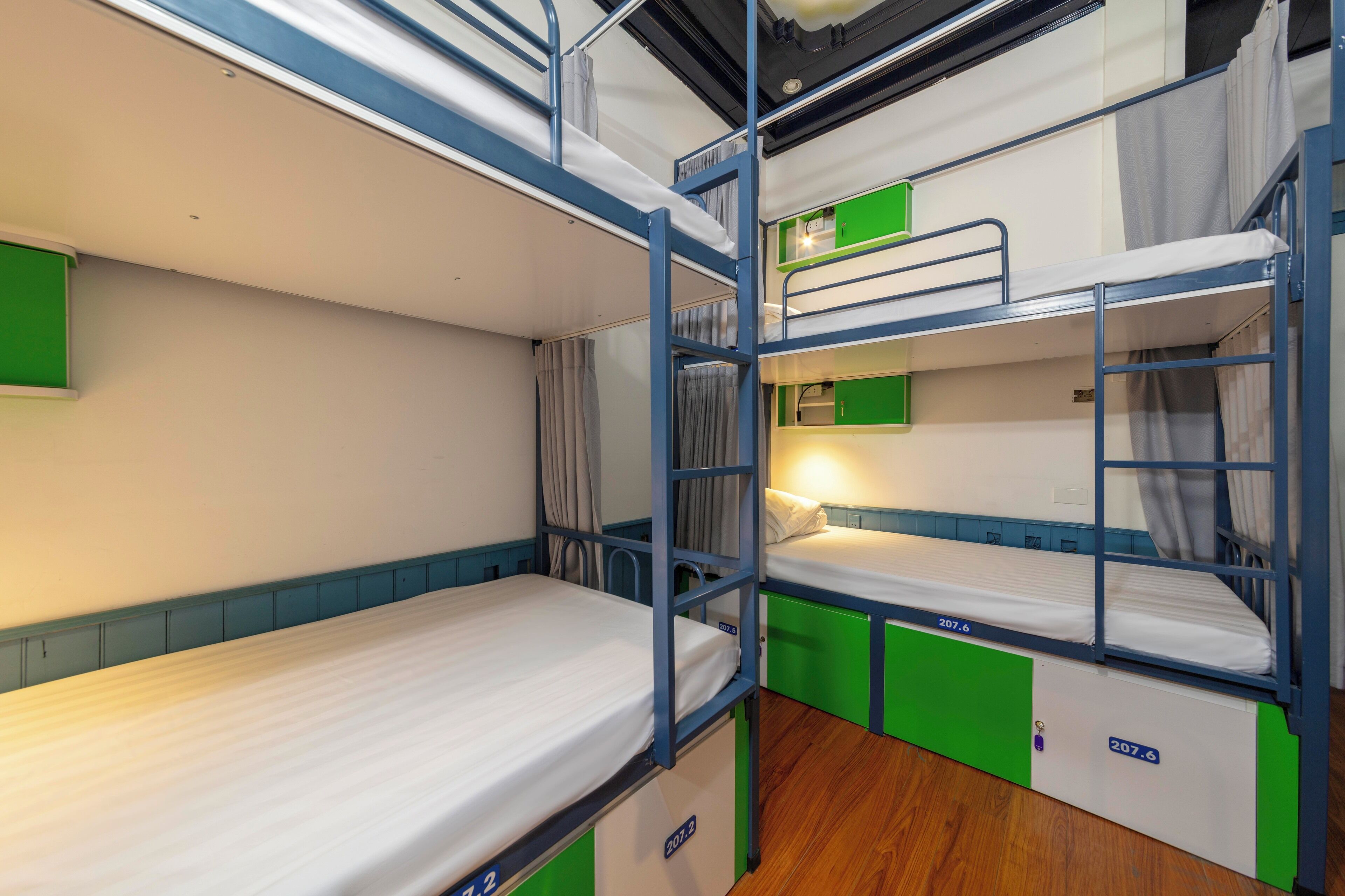 Une chambre avec des lits superposés, des touches de vert et un plancher en bois.