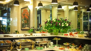 A buffet area with various food stations, a large floral centerpiece, and a mirror reflecting the space.