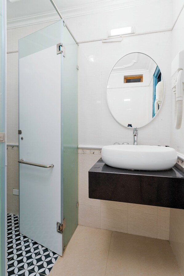 Un baño con puerta de vidrio, un lavabo blanco y un espejo.