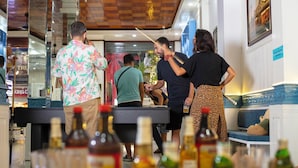 A bar area with a counter, bottles, and a seating area with a bench.
