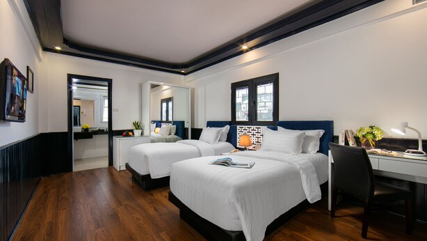 A hotel room with two beds, a desk, and a chair.