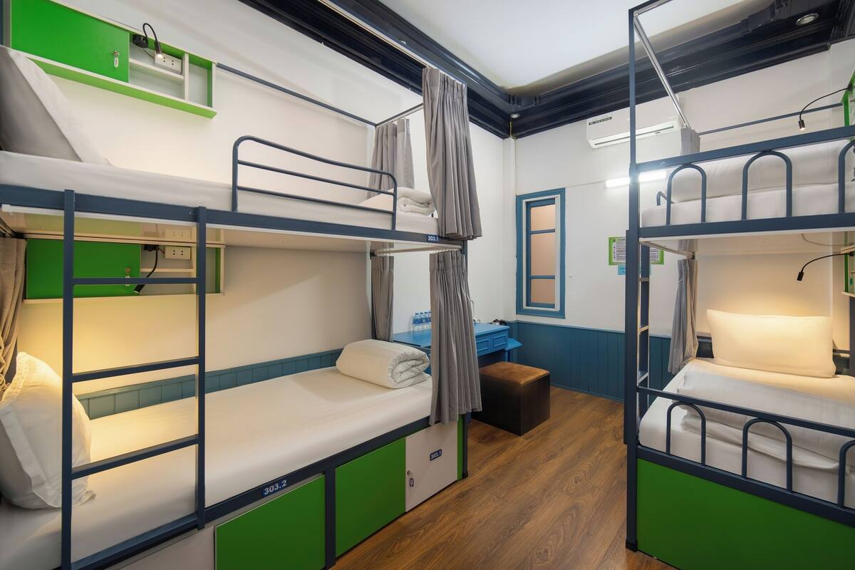 A room with bunk beds, a desk, and a small bathroom.
