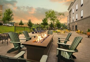An outdoor seating area with a fire feature, green chairs, and tables. - Hampton Inn and Suites New Hartford/Utica (New Hartford)