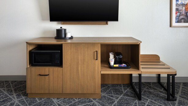 A compact hotel room with a wooden desk, a flat-screen TV, a microwave, and a coffee maker. - Hampton Inn and Suites New Hartford/Utica (New Hartford)
