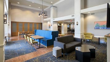 A hotel lobby with seating areas, a reception desk, and a staircase.