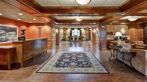 A hotel lobby with a reception desk, a large rug, wooden flooring, and a dining area in the background. - Hampton Inn and Suites New Hartford/Utica (New Hartford)