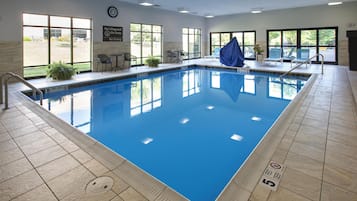 An indoor swimming pool with clear water, tiled floor, and a lifeguard sign on the wall.