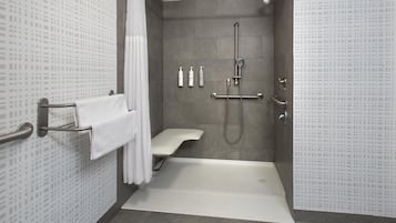 A modern bathroom with a shower, toilet, and grab bars.