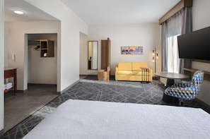 A hotel room with a bed, a sofa, a TV, a small table, and a chair. - Hampton Inn and Suites New Hartford/Utica (New Hartford)