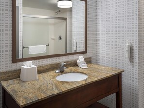 A bathroom with a granite countertop, a white sink, a mirror, and a towel rack. - Hampton Inn and Suites New Hartford/Utica (New Hartford)