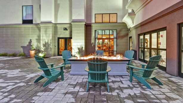 A courtyard with a fire feature, outdoor seating, and a restaurant entrance. - Hampton Inn and Suites New Hartford/Utica (New Hartford)