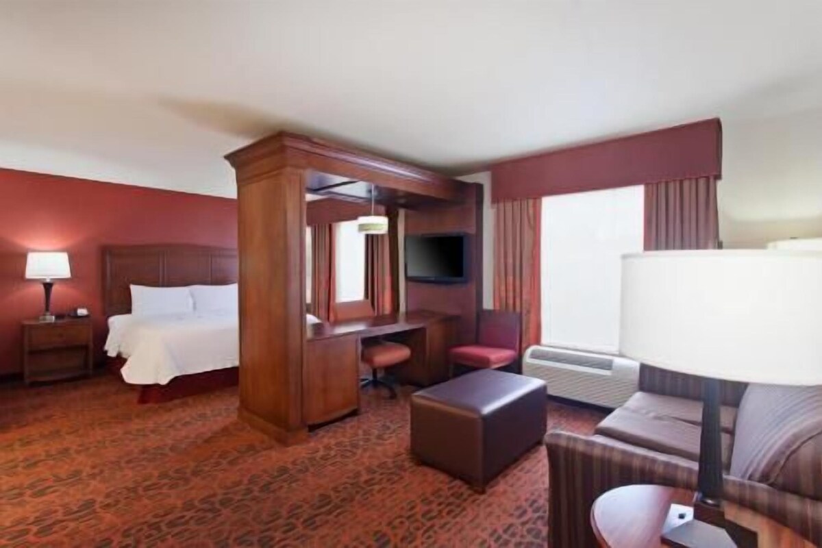 Une chambre d’hôtel équipée d’un lit, d’un bureau, d’une chaise, d’un canapé, d’une télévision et d’un appareil de climatisation.