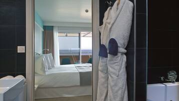 A hotel room with a bed, a bathtub, and a view of the sea.