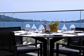 Enjoy a meal on the outdoor dining area with a scenic view of the water and distant hills.